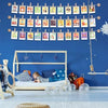 A display of small wooden clothespins with jute twine hanging against a blue wall, used for photo displays and crafts.