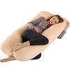A woman is lying down comfortably on a beige U-shaped maternity body pillow.