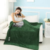 A dark green flannel cloak with a hood is draped over a white sofa in a bright room.