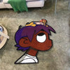 A plush cartoon character rug featuring a purple-haired figure with orange hair and yellow clothing on a gray carpet.