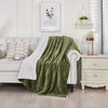 A green sherpa fleece blanket draped over a white sofa in a bright, modern living room.