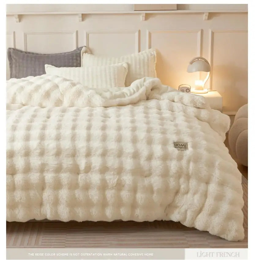 A fluffy white rabbit quilt comforter displayed on a bed with light wood flooring and neutral bedding.