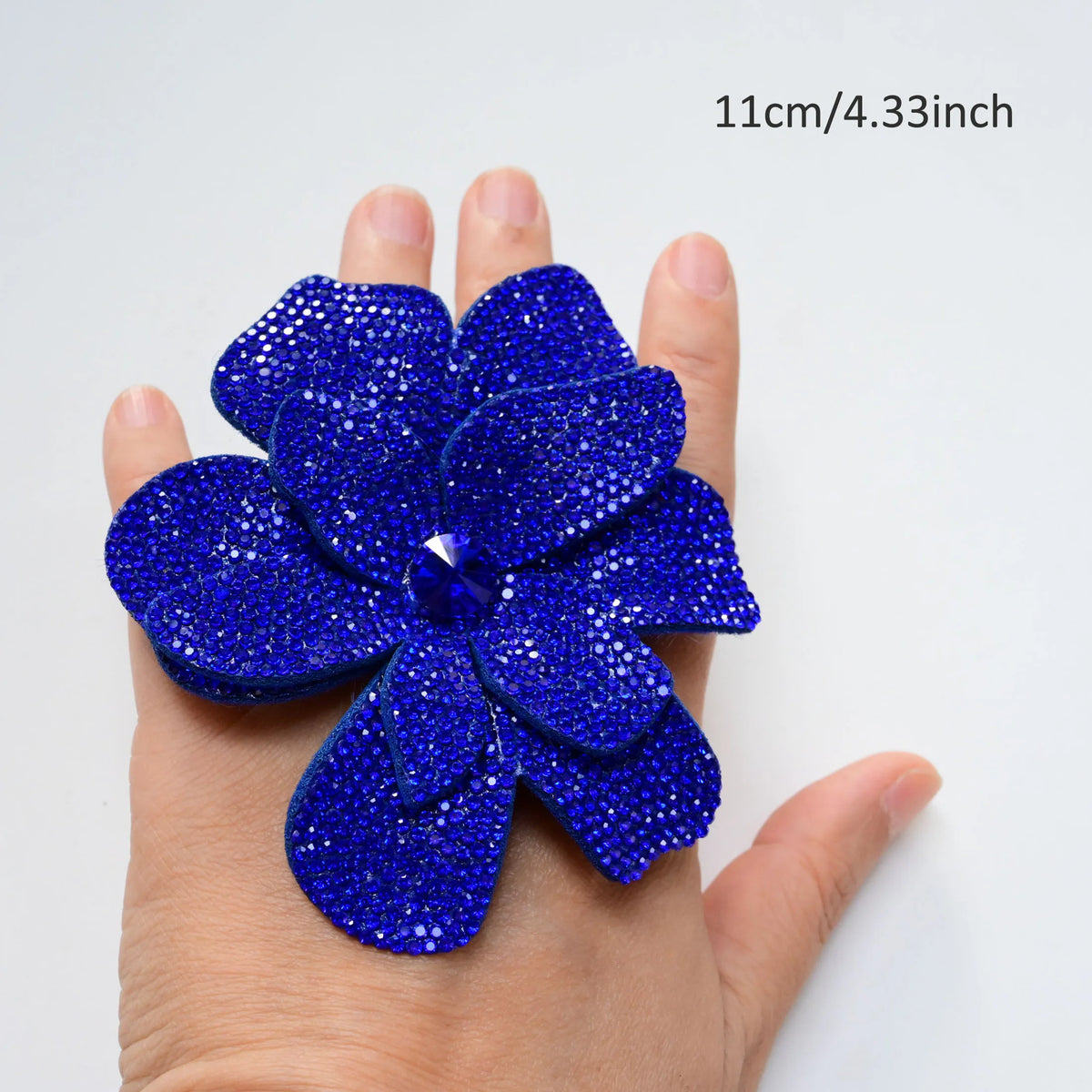 A hand holds a vibrant royal blue rhinestone flower applique patch, measuring 11cm or 4.33 inches.