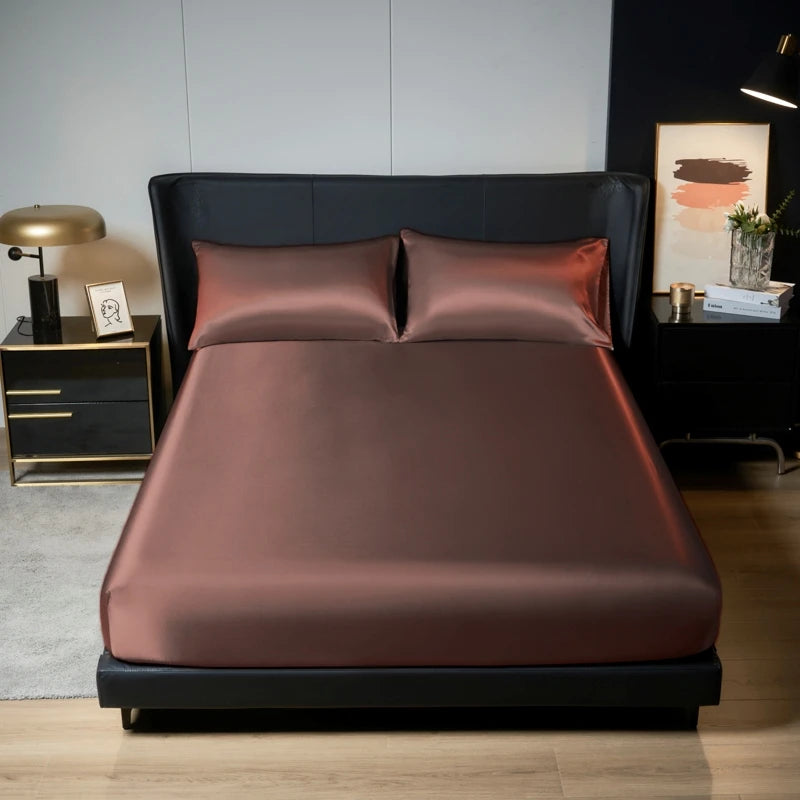 A luxurious brown satin bedding set displayed on a black bed with dark gray upholstery and modern decor.