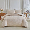 A beige luxury quilt duvet set displayed on a bed with white molding and light neutral decor.