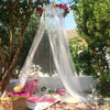 A sheer white mosquito net draped like a tent in an outdoor garden setting.