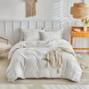 A white embossed leaf duvet cover set displayed on a bed with light wood accents and natural textiles.