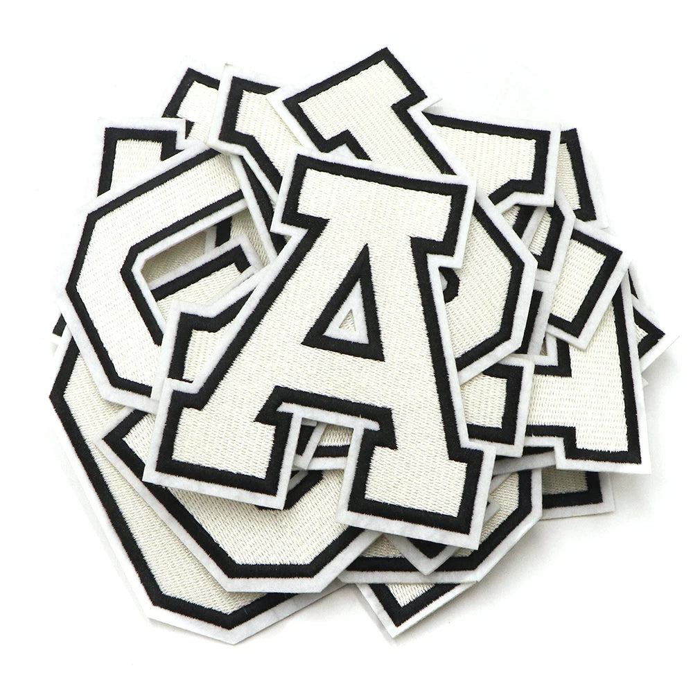 A pile of white and black letter patches, including the letter A, for clothing decoration.