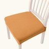 An orange quilted fabric seat cover placed on a white wooden dining chair.