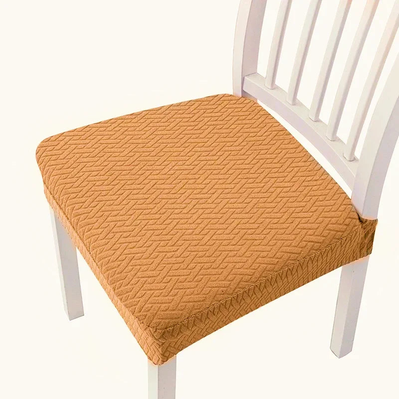 An orange quilted fabric seat cover placed on a white wooden dining chair.