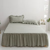 A plaid cotton bed skirt cover in olive green and beige tones is displayed over a bed.
