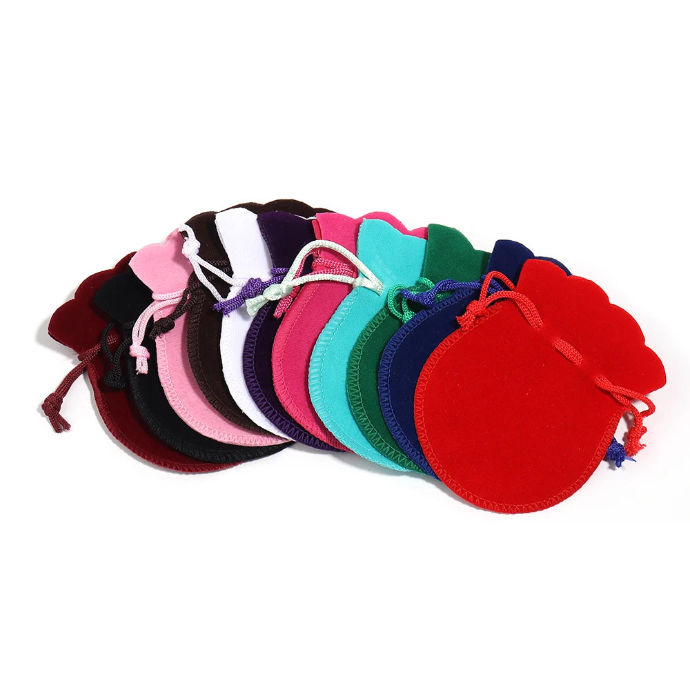 A set of ten velvet drawstring gift bags in various shades of pink, purple, green, and red.