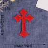 A single red cross embroidery patch on a dark blue fabric background.