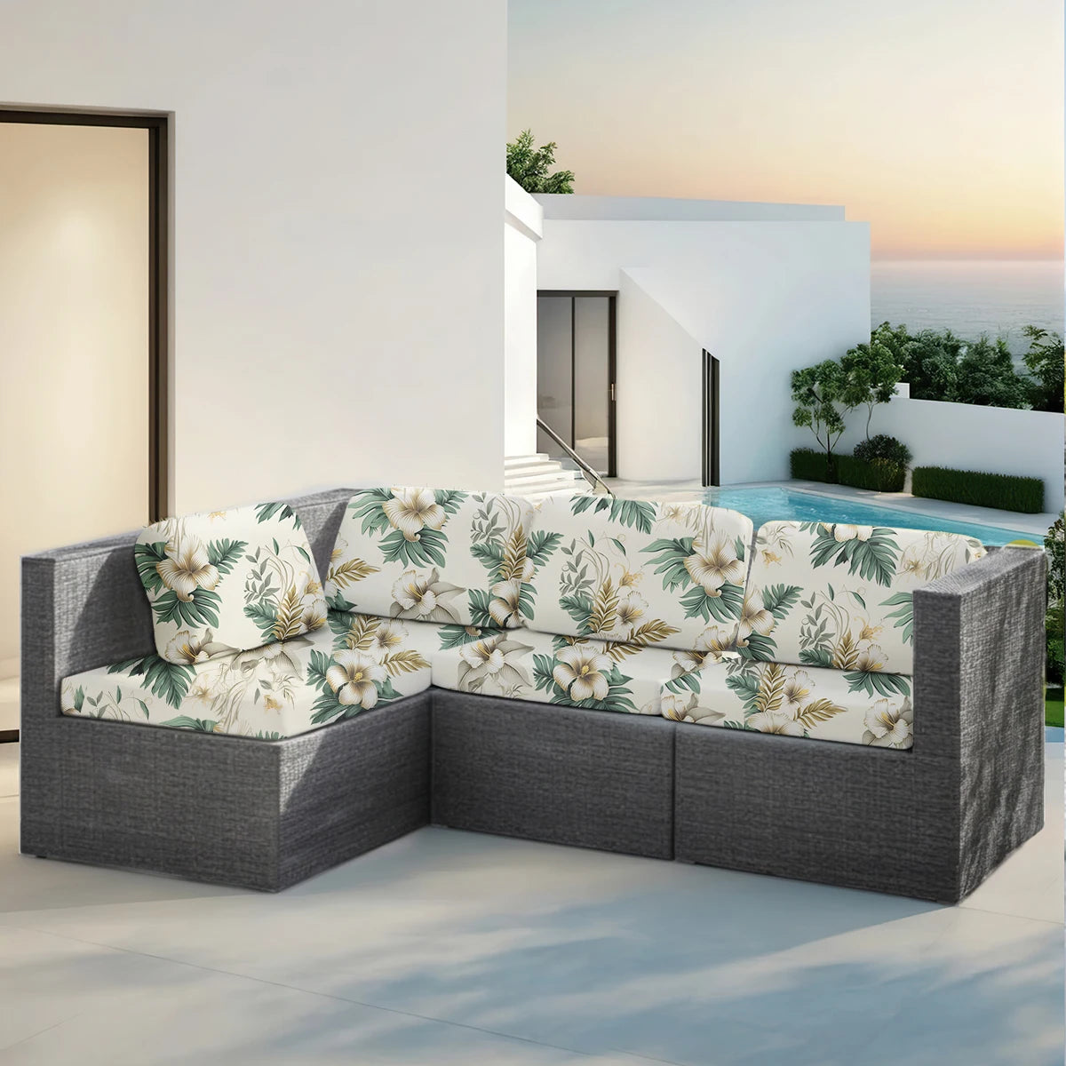 A gray outdoor sofa featuring floral patterned cushions set on a patio near the ocean.