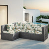 A gray outdoor sofa featuring floral patterned cushions set on a patio near the ocean.
