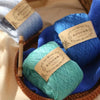 A collection of blue and teal yarn balls wrapped in natural fiber baskets for crafting