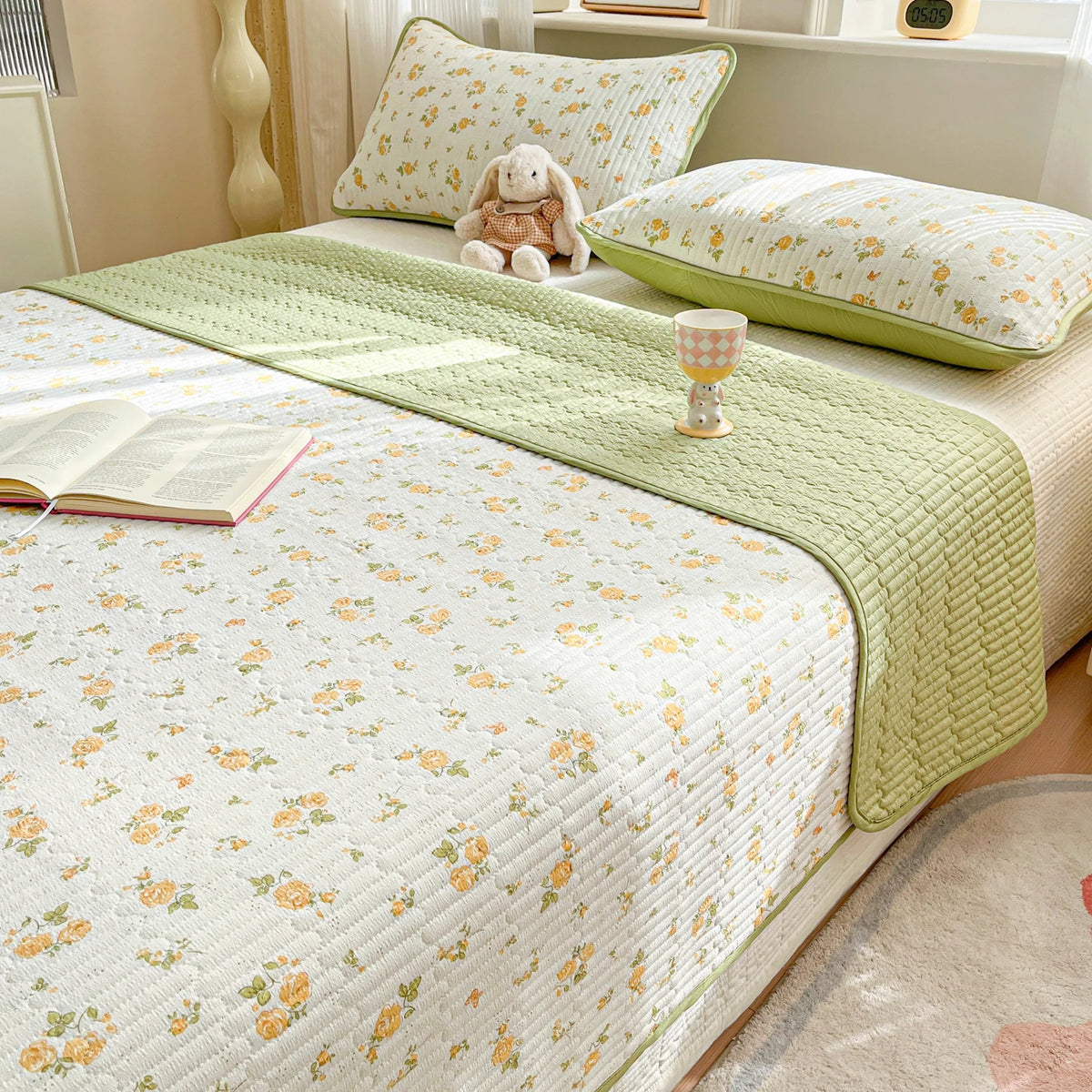 A luxury floral quilted bedspread with a light green trim and matching pillows on a bed.