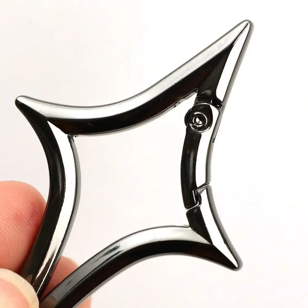 A close-up of a black Gothic Y2K star alloy key ring buckle being held by a hand.