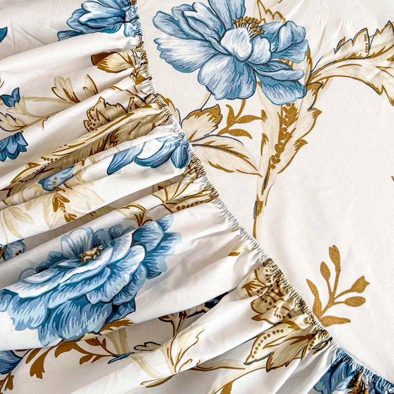 White bed sheet with a blue and gold floral print featuring large blossoms and leaves.