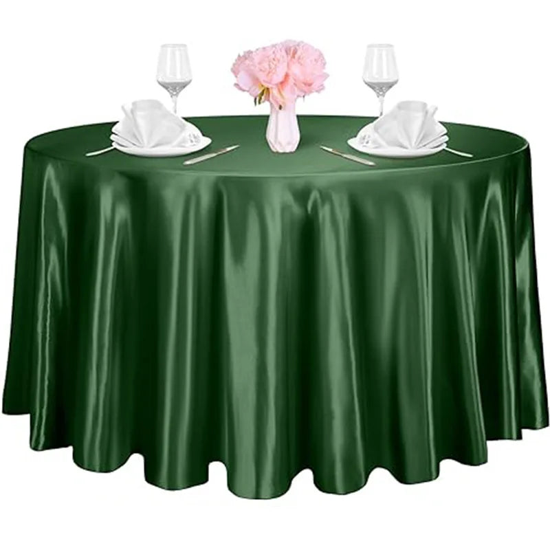 A dark green satin table overlay set for an event featuring pink flowers and glassware.