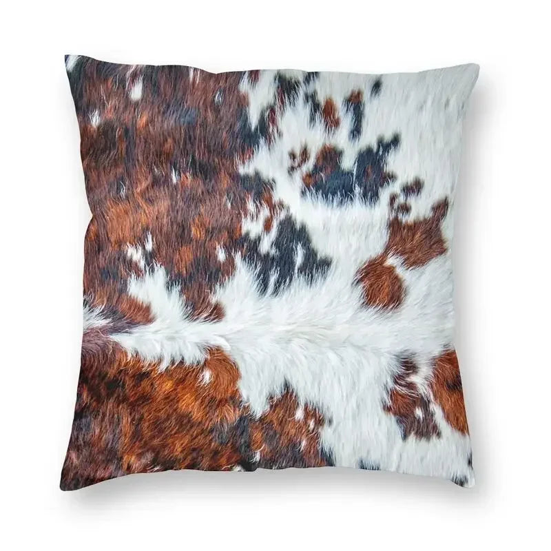 A square cushion cover made of faux fur cowhide print featuring brown and white patches.