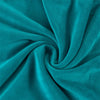 A close-up of a teal velvet fabric gathered into a swirl, showing the texture and drape.