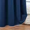 A dark navy blue blackout window curtain draped next to a window with a view of green hills.