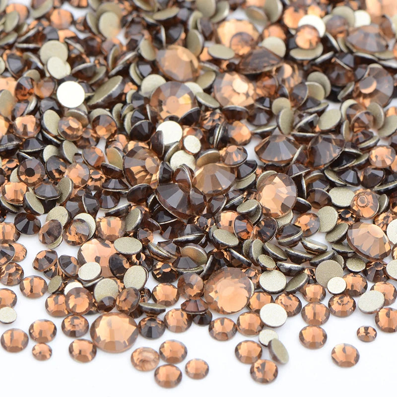 A close-up view of a mix of brown and gold clear glass rhinestones for DIY crafts.