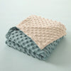 A folded baby name swaddle blanket in soft peach and gray fleece fabric.
