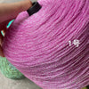 A close-up of magenta glitter metallic yarn being held by a hand, showing the texture and color of the fiber.