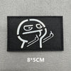 A black embroidered patch featuring a stylized, grinning face design.