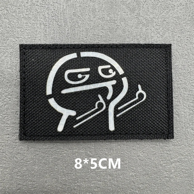 A black embroidered patch featuring a stylized, grinning face design.
