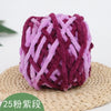 A ball of purple and magenta chenille knitting yarn resting on a woven straw mat.