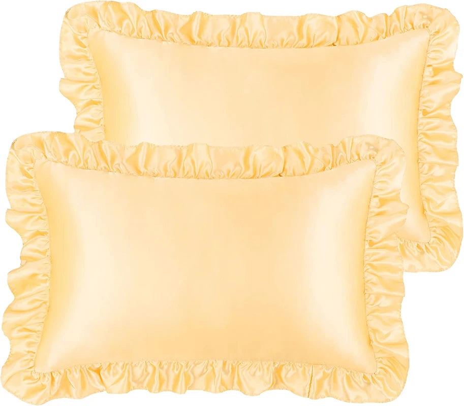 A set of two ruffled satin pillowcases in a pale yellow color with silky envelope closures.