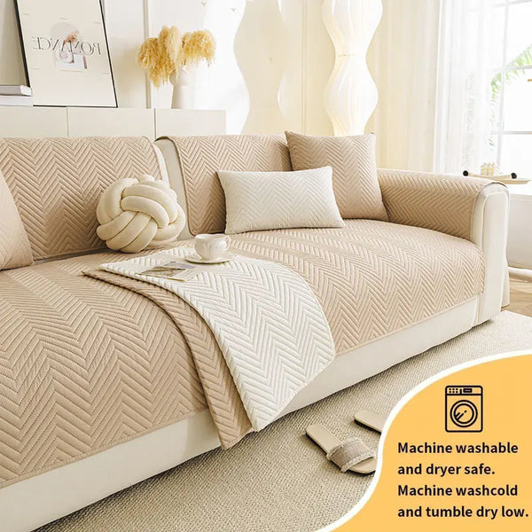A beige anti-slip fabric sofa cushion cover displayed on a light-colored sofa with matching pillows and a decorative throw.