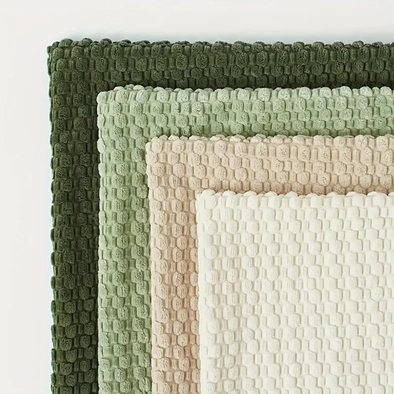 A stack of decorative pillow covers in various pastel and olive green shades with textured stitching.
