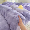 A close-up of a purple cozy rabbit fleece duvet cover with a yellow accent, being touched by a hand.