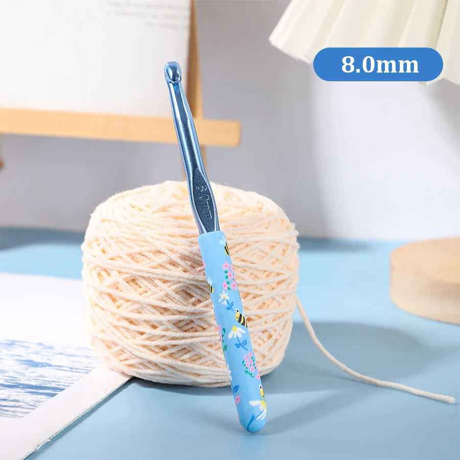 A blue ergonomic crochet hook with a 8.0mm tip is shown next to a ball of light pink yarn.