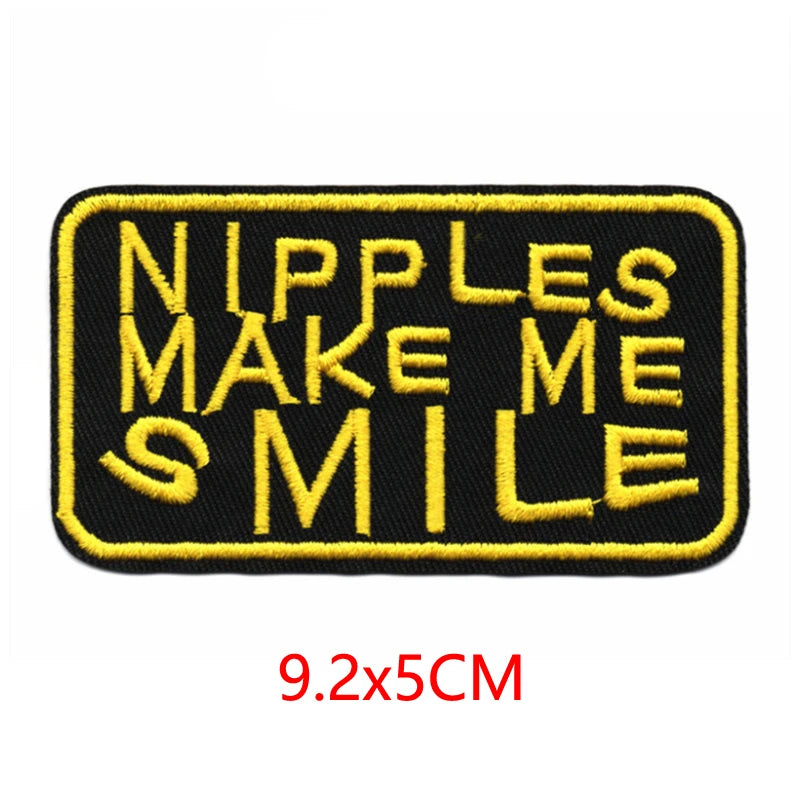 Black embroidered patch with yellow text that reads Nipples Make Me Smile