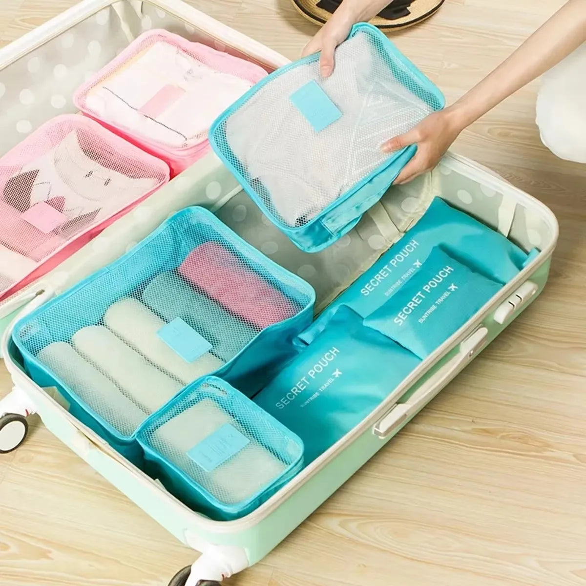 A light green travel organizer storage set with multiple mesh and fabric pouches is shown being handled.