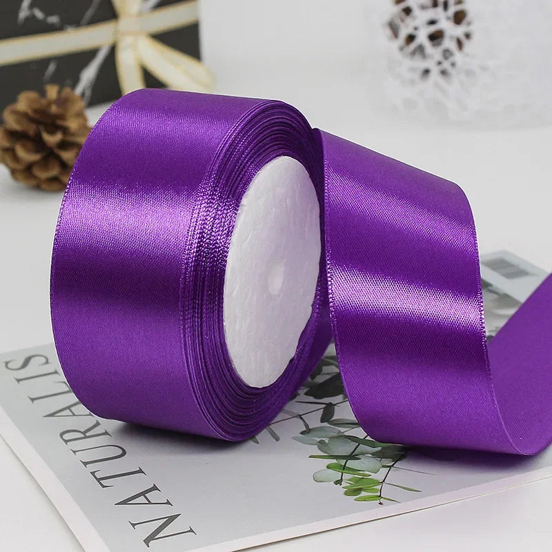 Purple satin craft ribbon rolled and unrolled on a white background.