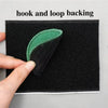 A close-up of a black fabric with a green hook and loop backing, showing the texture and stitching.