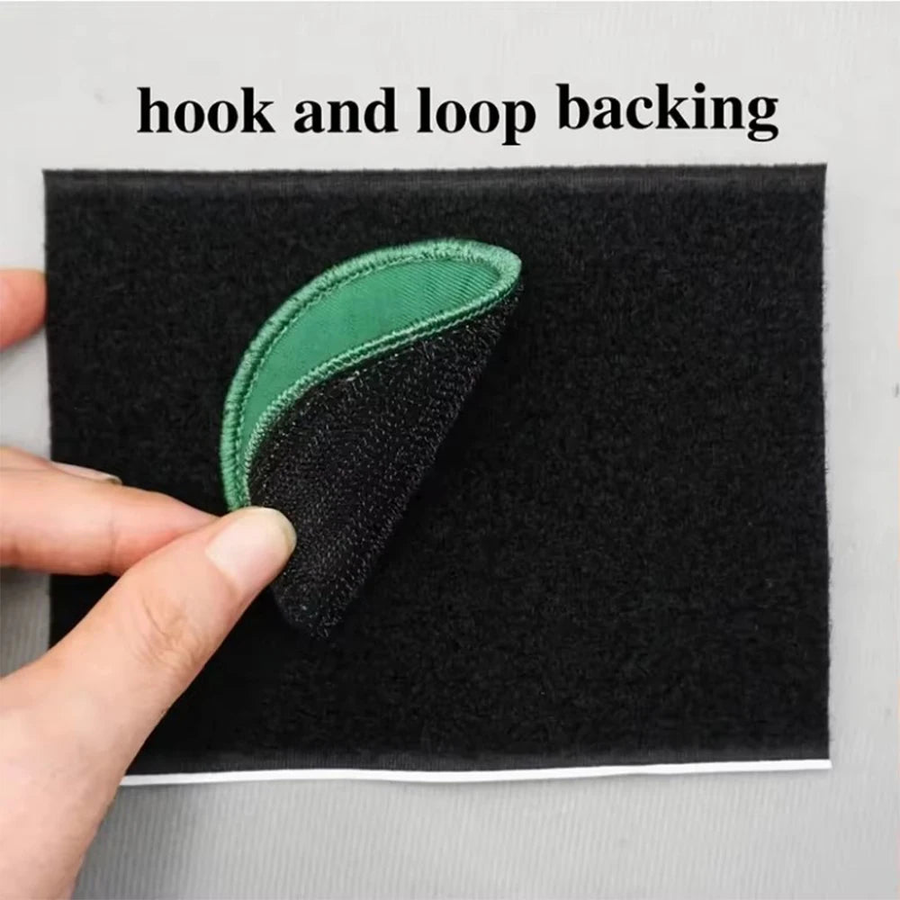 A close-up of a black fabric with a green hook and loop backing, showing the texture and stitching.