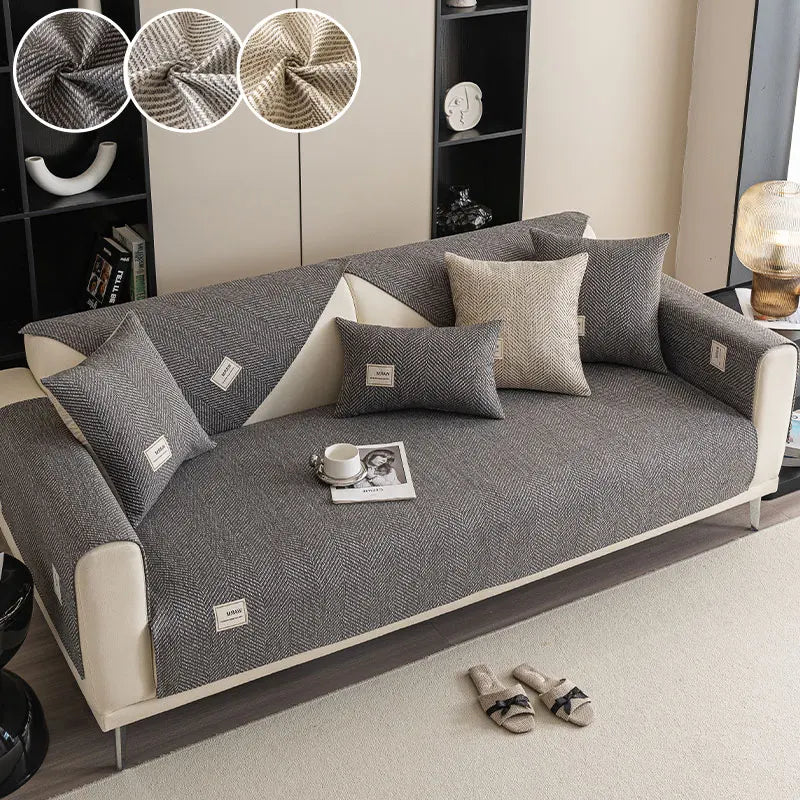 A modern gray sofa with light beige cushions and a small white book on the seat.