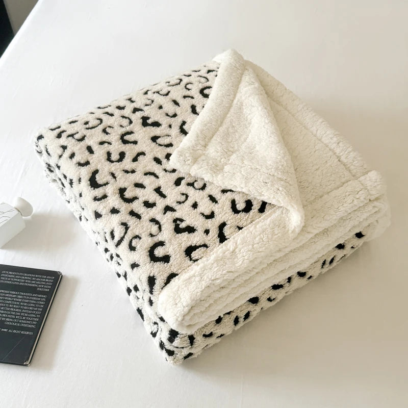 A leopard print jacquard knit throw blanket folded on a white surface.