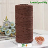 A roll of medium-thick brown hand-woven cotton yarn for crafting, next to a pink rose flower.