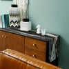 A modern abstract marble linen table runner displayed on a wooden cabinet with decorative items.