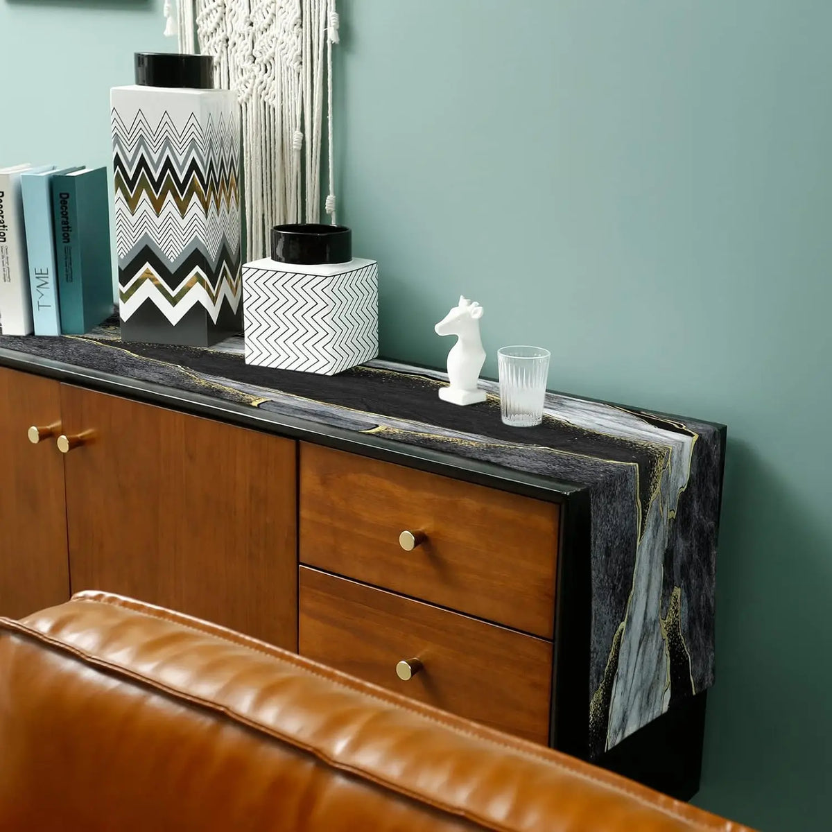 A modern abstract marble linen table runner displayed on a wooden cabinet with decorative items.