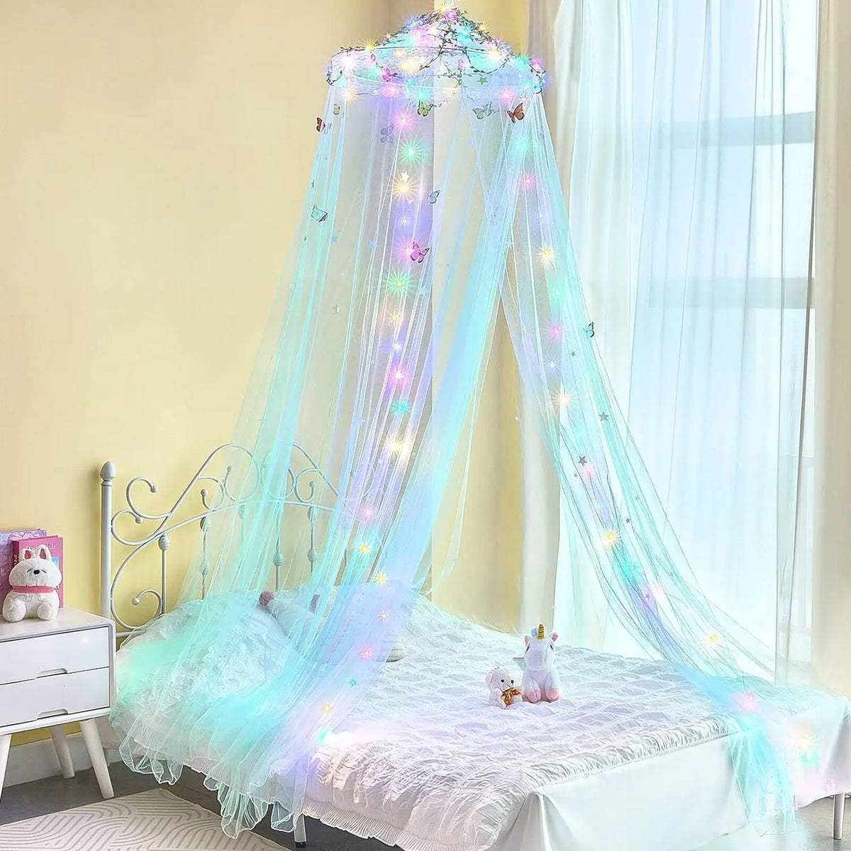 A sheer, light blue mosquito net bed curtain with sparkling lights hangs over a white bed.