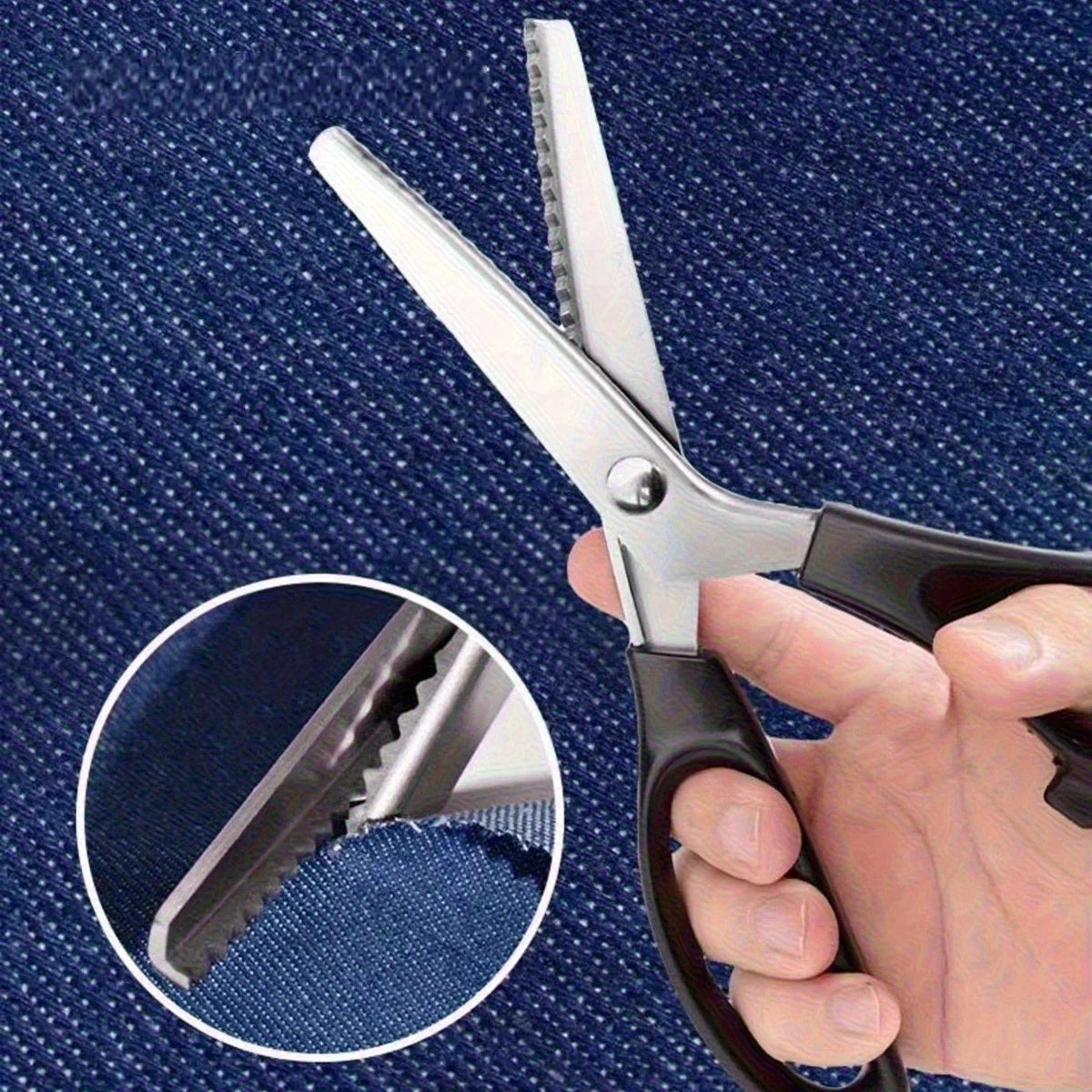 A hand holds a pair of stainless steel serrated edge fabric scissors against a dark blue fabric background.